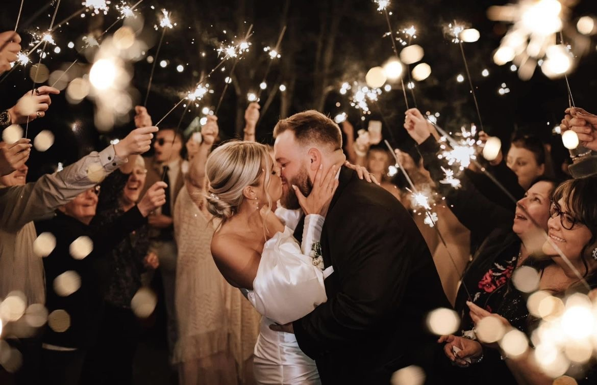 Un couple de mariés s'embrasse sous les lumières de la soirée